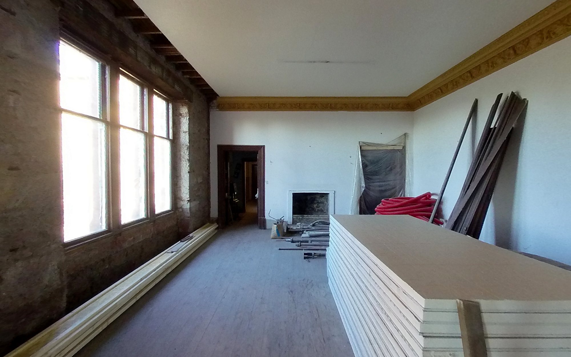 The dining room in January 2021: bare stone walls under the garden windows and boards stacked on the floor