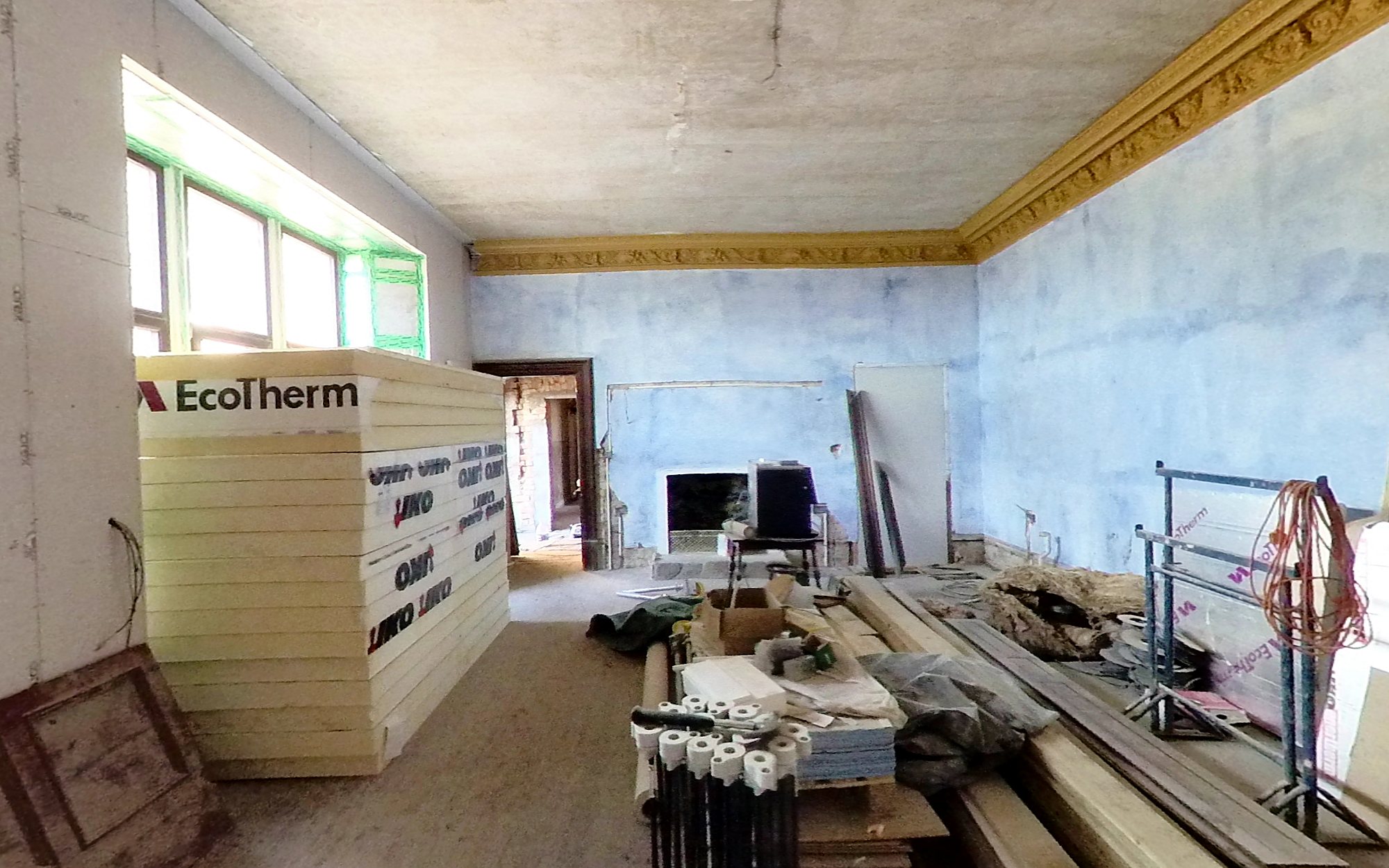 The same dining room in April 2022: walls plastered, gold cornice up and insulation boards stacked by the window