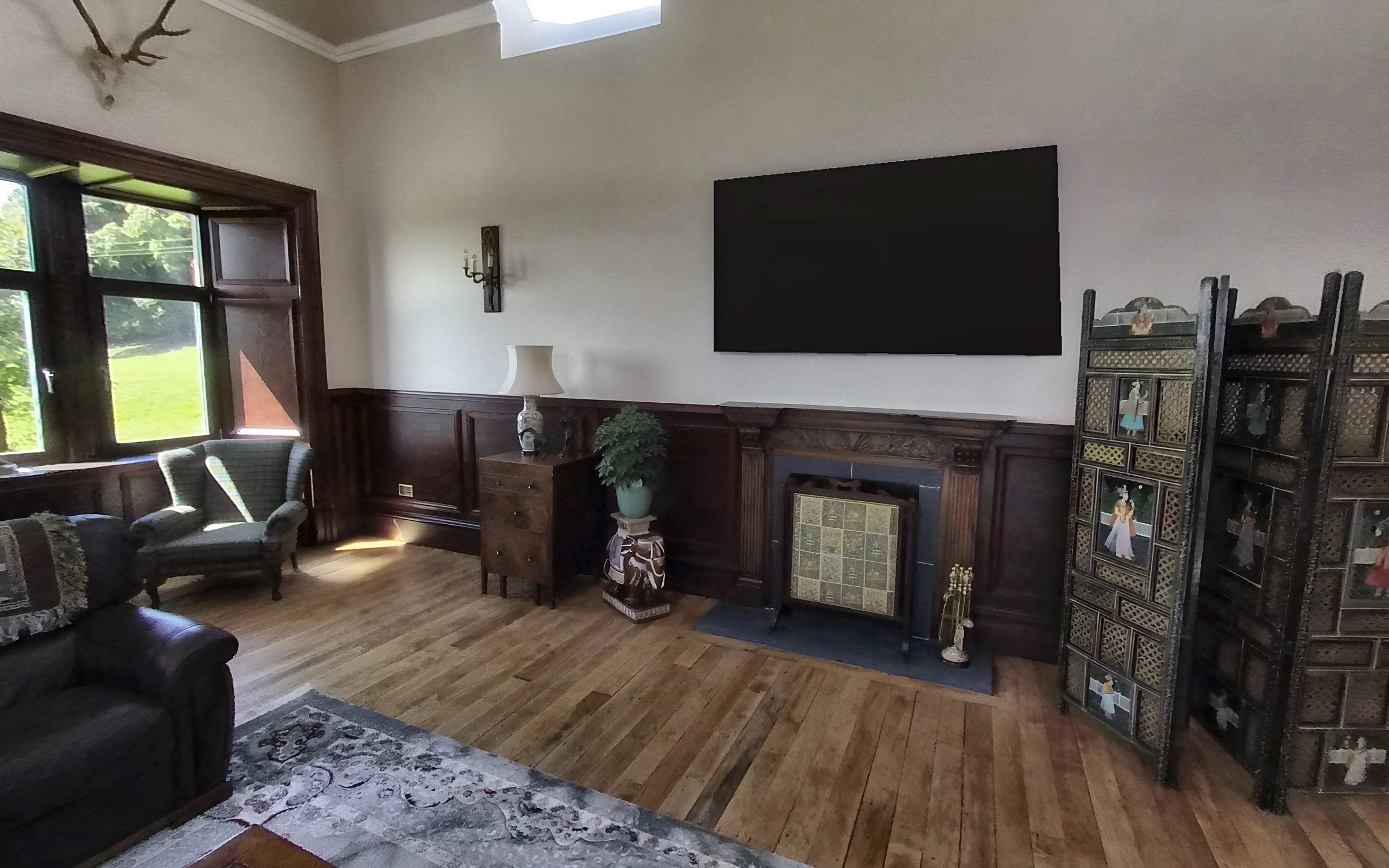 Still from a 360 tour: a finished lounge with panelling, fireplace and bay window