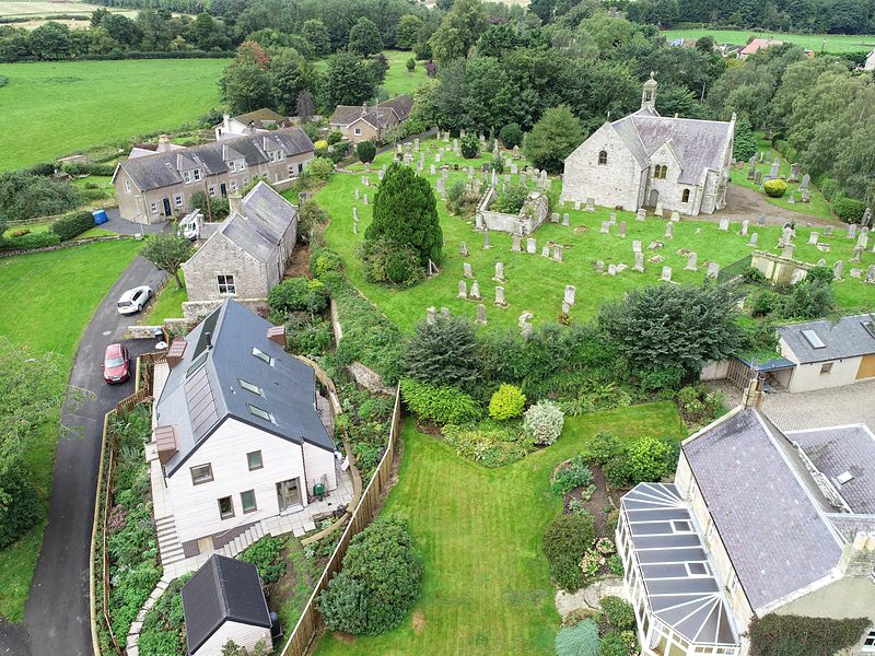 The house from the lane, with the church and fields behind
